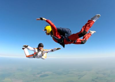 Élève parachutiste en chute libre, encadré par un moniteur pendant une formation PAC